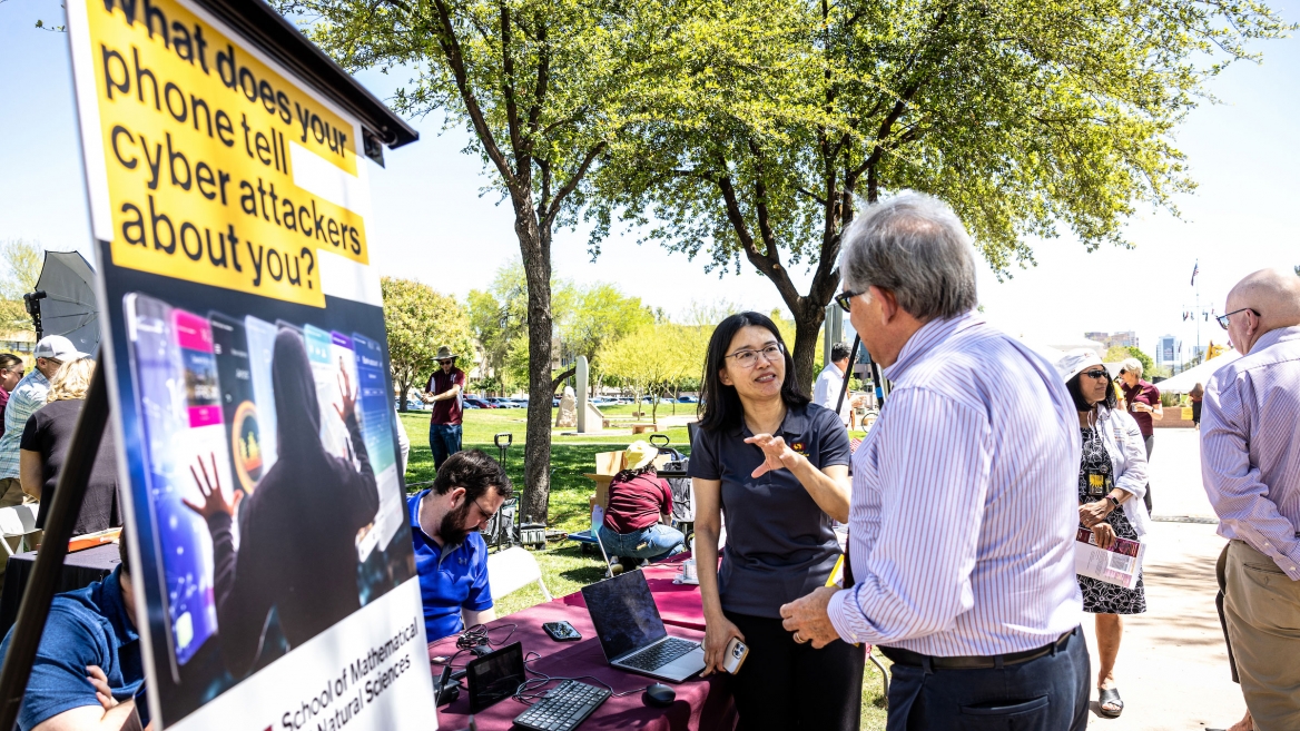 Two people talking at table at outdoor event at Arizona Capitol