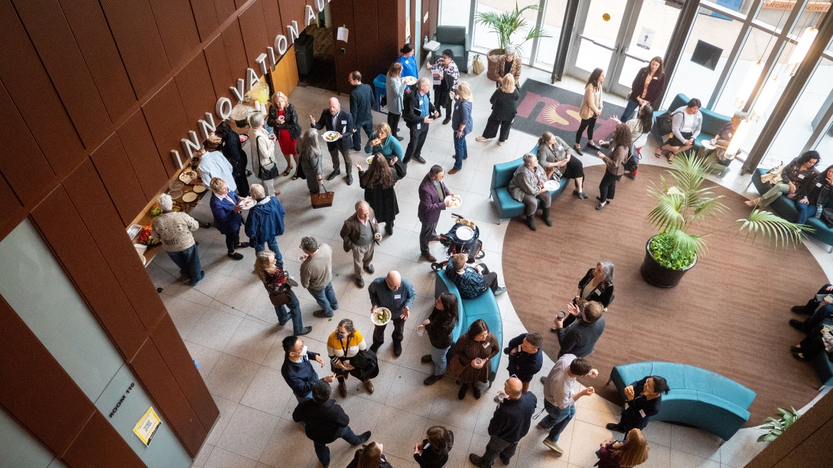 Overhead view of a group of people mingling in the lobby below at the Edson College of Nursing and Health Innovation