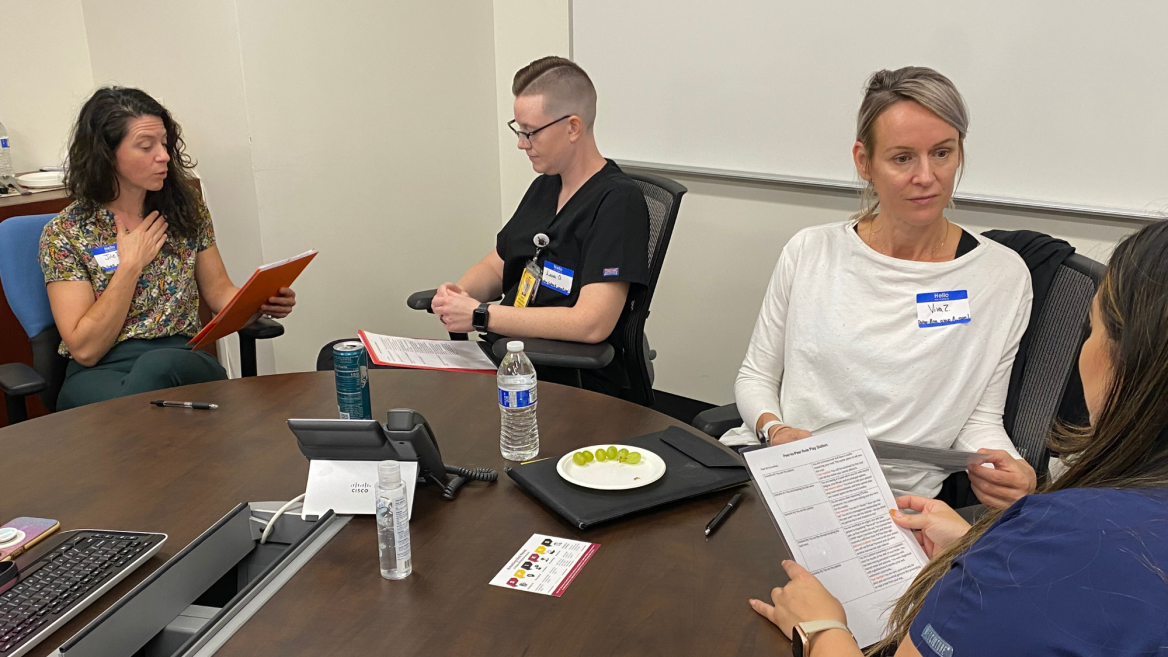 Four doctor of nursing practice students sit around a conference table engaged in conversation as part of an educational workshop 