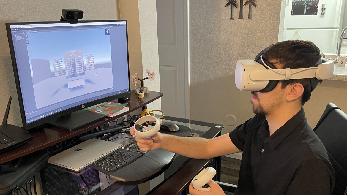 Man wearing a VR headset seated in front of a computer.